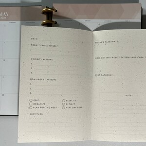 May include: A monthly planner with a calendar for May 2024, a section for daily notes, and a section for weekly reflections. The planner has a cream-colored paper with a speckled texture.