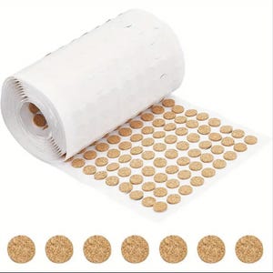 Könnte beinhalten: Eine Rolle selbstklebender Korkpunkte, ideal zum Aufhängen von leichten Gegenständen an Wänden, ohne diese zu beschädigen. Die Rolle ist teilweise abgewickelt und zeigt die Korkpunkte in einem Rastermuster. Unter der Rolle sind auch einzelne Korkpunkte abgebildet.