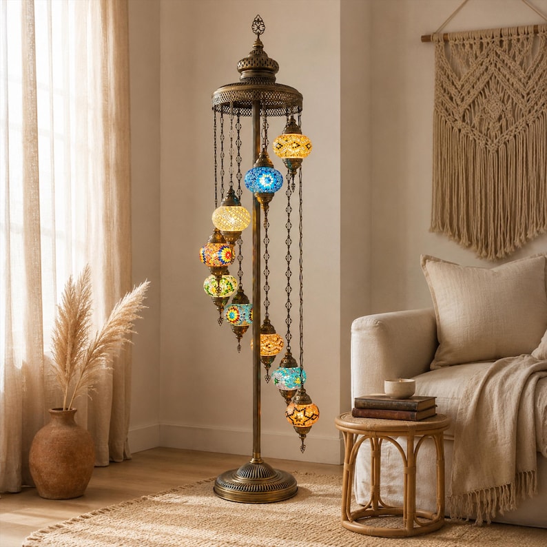 May include: A bronze-colored floor lamp with a spiral design, featuring multiple colorful mosaic glass globes. The lamp has a decorative top and base, with the globes hanging from chains. The lamp is in a living room setting.