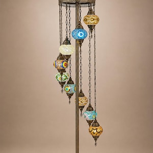May include: A tall floor lamp with a bronze-colored metal stand and base, featuring nine hanging mosaic glass globes in various colors including blue, yellow, green, and white. Each globe is suspended by a metal chain from a circular top frame.