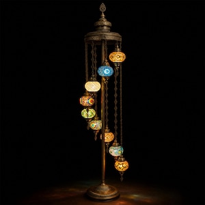 May include: A tall, ornate floor lamp with a bronze finish. It features a spiral of colorful, mosaic-style glass globes in various colors, including blue, yellow, and orange. The lamp has a decorative top and base, and the globes hang from chains.