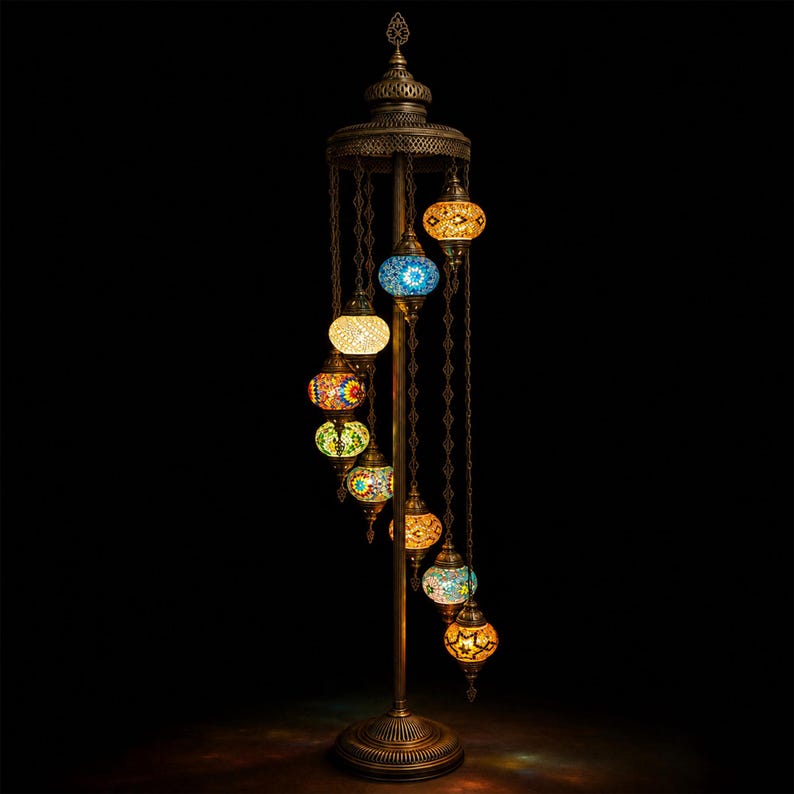 May include: A tall, ornate floor lamp with a bronze finish. It features a spiral of colorful, mosaic-style glass globes in various colors, including blue, yellow, and orange. The lamp has a decorative top and base, and the globes hang from chains.