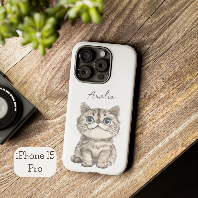 Personalized phone case featuring a cute cartoon cat design with a customizable name, available for iPhone, Samsung, and Google Pixel models.