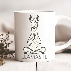 May include: White ceramic mug with a black and white illustration of a llama in a yoga pose. The text "LLAMASTE" is printed below the llama.
