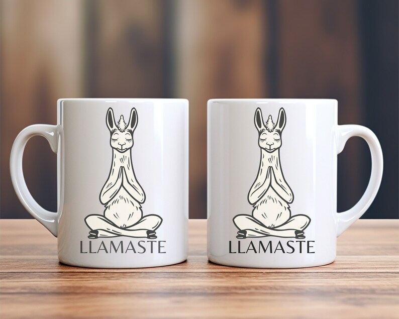 May include: Two white ceramic mugs with black illustrations of llamas in a yoga pose. The text "LLAMASTE" is printed on the bottom of each mug.