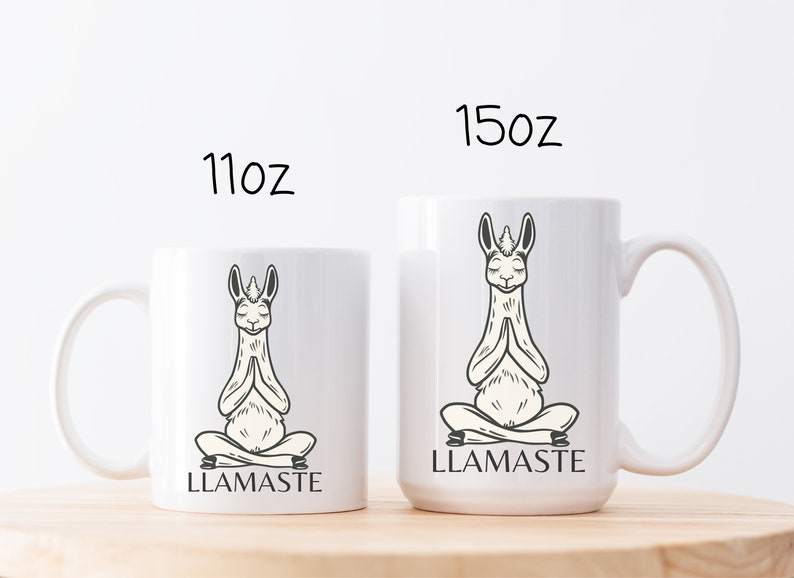 May include: Two white ceramic mugs with a black and white illustration of a llama in a yoga pose. The text "LLAMASTE" is printed on the mugs. The mugs are 11 oz and 15 oz.