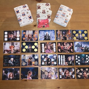 Könnte beinhalten: Eine Sammlung von Harry-Potter-Artikeln, darunter Spielkarten mit Charakteren und Szenen aus den Filmen sowie weiße Geldbörsen mit Teddybärmuster. Ein kleines Paket mit rosa Artikeln ist ebenfalls vorhanden.