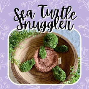 May include: A handmade crochet sea turtle in a wooden bowl. The turtle has a green head and flippers, and a brown shell. The text "Sea Turtle Snuggler" is above the turtle.