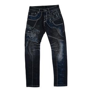 Puede incluir: Vaqueros de mezclilla azul oscuro con costuras blancas y un diseño de patchwork. Los vaqueros tienen el texto "K&M" y "OSMO LUPO" bordado.