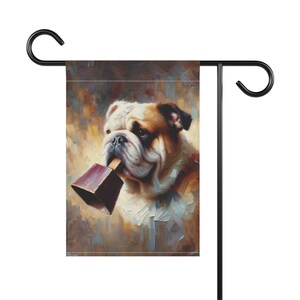 Garden flag featuring a painted portrait of a bulldog holding a maroon cowbell in its mouth, with a warm, abstract background that creates a charming and whimsical atmosphere.