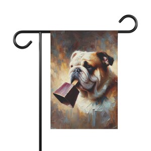 Garden flag featuring a painted portrait of a bulldog holding a maroon cowbell in its mouth, with a warm, abstract background that creates a charming and whimsical atmosphere.