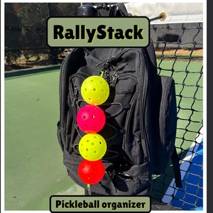 May include: Black backpack with four pickleballs attached. The pickleballs are yellow and red. The text "RallyStack" and "Pickleball organizer" are displayed on the image.