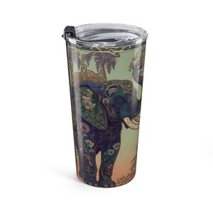 May include: A travel mug featuring an ornate illustration of a blue elephant with floral and peacock feather details. The design includes the text "L'éléphant" and is set against a light green and peach background. The mug has a black lid.