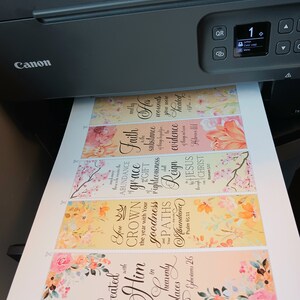 May include: A set of six printable bookmarks with floral designs and inspirational quotes. The bookmarks feature a yellow background with pink and white flowers. The quotes include "Seated with Him in heavenly places", "You Crown the year with Your goodness", "Faith in His wounds", "Abundance of grace", "Your paths righteousness", and "Reign in Jesus Christ".