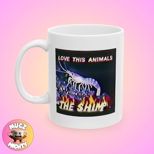 Op de afbeelding: Witte keramische mok met een kleurrijk beeld van een garnaal in brand. De tekst "LOVE THIS ANIMALS THE SHIMP" staat op de mok gedrukt.