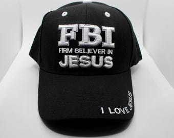 以下が含まれることがあります： 前面に「FBI FIRM BELIEVER IN JESUS」と白い刺繍が施された黒い野球帽。「I LOVE JESUS」というフレーズが縁に刺繍されています。帽子の上部には白いボタンが付いています。