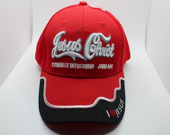 May include: Red baseball cap with a white embroidered design that says "Jesus Christ Eternally Refreshing John 4:14". The brim of the cap is black with a white trim and the words "I Love Jesus" are embroidered on the side.
