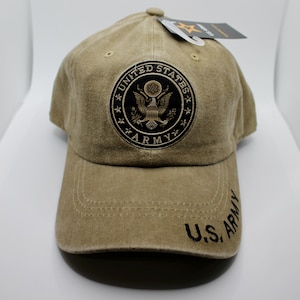 May include: A khaki baseball cap with a black embroidered patch featuring the United States Army seal. The seal has a gold eagle and the words "United States Army". The cap also has the words "U.S. Army" embroidered on the brim.