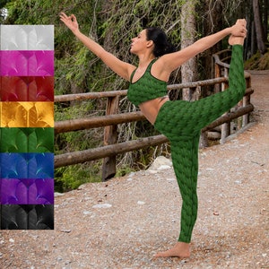 May include: A woman wearing a green yoga outfit with a leafy pattern is performing a yoga pose on a wooden bridge. The bridge is situated over a path in a forest.