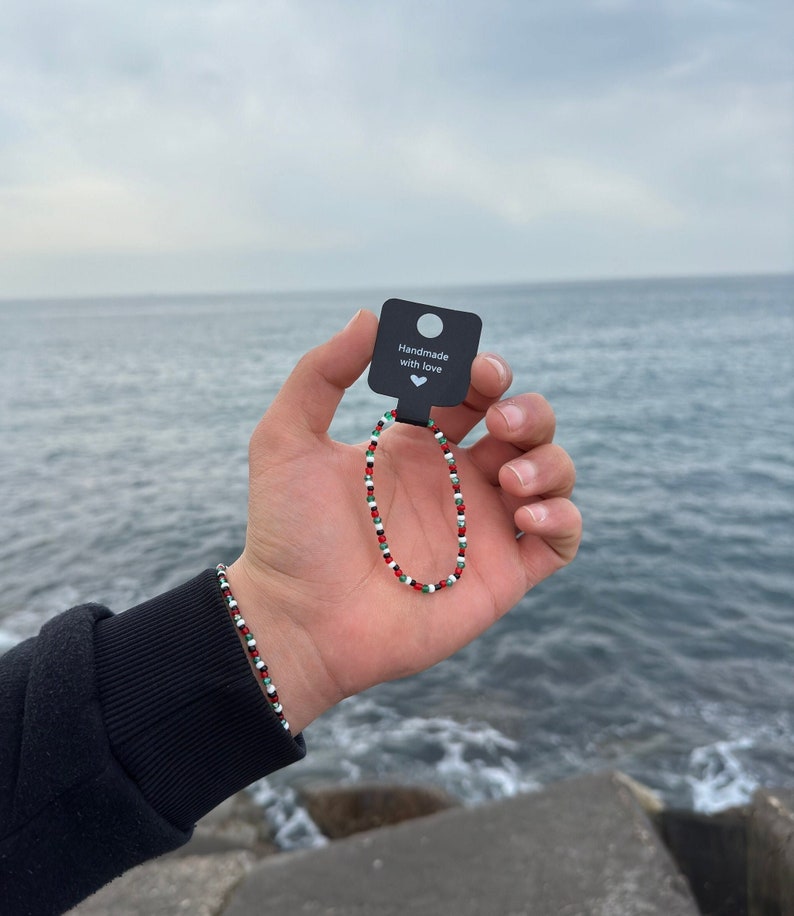 Photo of a hand holding a Palestine beaded bracelet.