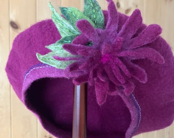 Un charmant béret avec une broche fleurie fantaisiste. Un cadeau pour un amateur de chapeaux. Un ajout féminin à une garde-robe de mode durable.