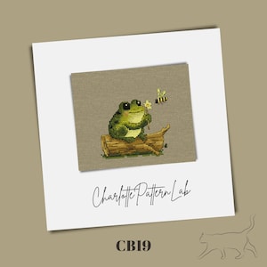 May include: Cross stitch pattern featuring a green frog sitting on a log, holding a flower with a bee flying nearby. The pattern is titled "CB19" and is from Charlotte Pattern Lab.