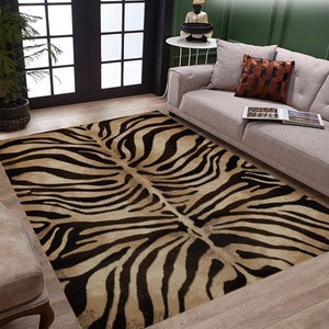 Può includere: Un tappeto da area a stampa zebra marrone e nero con una texture morbida e soffice. Il tappeto è steso su un pavimento in legno in un soggiorno.