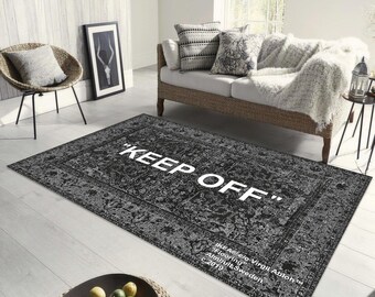 May include: Black and white area rug with a distressed pattern and the text "KEEP OFF" in white lettering. The rug also includes the text "IKEA e/o Virgil Abloh TM Flooring Almhult, Sweden c. 2019".