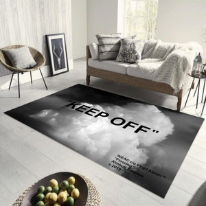 Può includere: Tappeto bianco e nero con un design a nuvole e il testo "KEEP OFF" in grassetto in lettere bianche. Il testo "IKEA® c/o Virgil Abloh™" è in lettere nere più piccole sotto il testo principale.