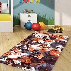 Puede incluir: Una alfombra colorida con un patr&oacute;n de muchas caras de perros. La alfombra est&aacute; sobre un suelo de madera en una habitaci&oacute;n con una mesita de noche blanca, un cami&oacute;n de juguete y un letrero que dice "TOYS".