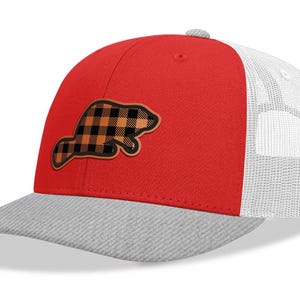May include: A red and gray baseball cap with a white mesh back. The cap features a black and orange plaid beaver patch on the front.