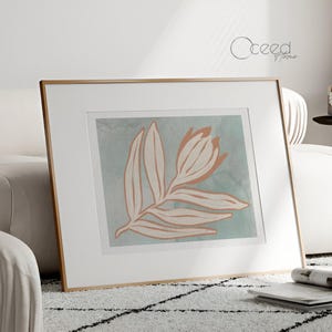 Puede incluir: Una impresión enmarcada de un diseño floral estilizado con una flor de melocotón claro y hojas sobre un fondo azul claro.