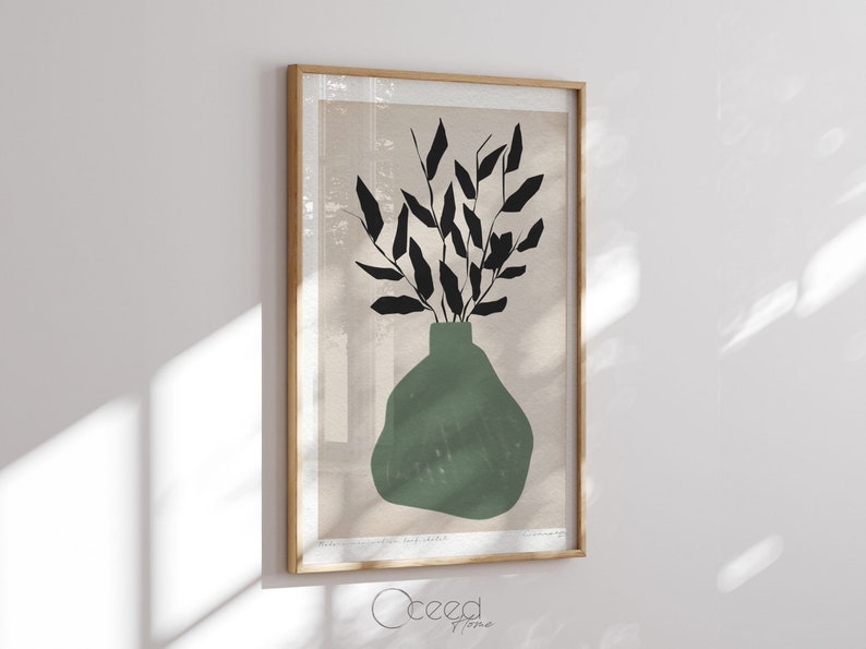 K&ouml;nnte beinhalten: Ein gerahmter Druck einer minimalistischen Illustration einer gr&uuml;nen Vase mit schwarzen Bl&auml;ttern. Der Hintergrund ist hellbeige.