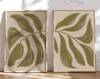 May include: Two framed prints with a minimalist design of a green leaf on a beige background. The prints are in wooden frames.