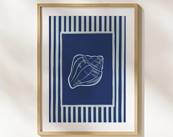 Puede incluir: Impresión artística enmarcada con una ilustración de concha blanca sobre un fondo azul marino. La obra de arte está enmarcada en un marco de madera clara y tiene un borde a rayas en blanco y azul marino. La impresión está etiquetada como "Creed Home".