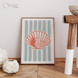 May include: A framed art print with a coral seashell design set against light blue and white vertical stripes. The artwork is in a wooden frame, creating a coastal aesthetic. The print evokes a seaside theme.