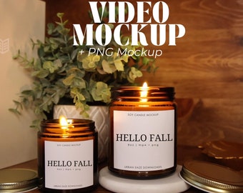 May include: Two amber glass soy candles with white labels that say "Soy Candle Mockup" and "Hello Fall 9oz | mp4 + png" with the text "Urban Daze Downloads" below. The candles are lit and sitting on a white surface.