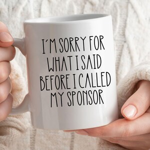 May include: White ceramic coffee mug with black text that reads "I'm sorry for what I said before I called my sponsor".