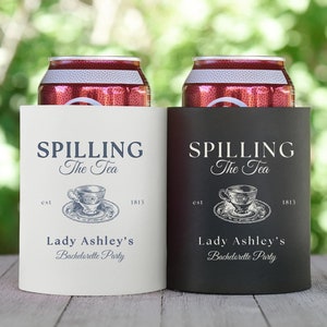 May include: Two white and black can coolers with the text "Spilling the Tea" and a vintage teacup illustration. The text "Lady Ashley's Bachelorette Party" is also included on each cooler.