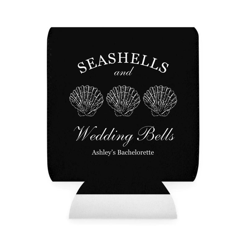 Może przedstawiać: Czarny kubek na napoje z białym tekstem i grafiką muszli. Tekst brzmi "Seashells and Wedding Bells" z "Ashley's Bachelorette" poniżej. D&oacute;ł jest biały.