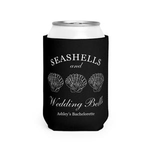 Może przedstawiać: Czarny kubek na puszkę z białym tekstem i ilustracjami muszli. Tekst brzmi "Seashells and Wedding Bells" z "Ashley's Bachelorette" poniżej. Projekt zawiera trzy ilustracje muszli.