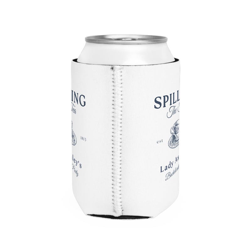 May include: White can cooler with a blue and white design. The text on the cooler reads "Spilling The Tea est. Lady As... Bottled and Brewed".