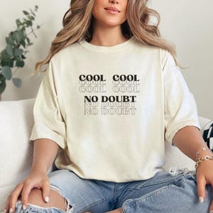 May include: A white t-shirt with the text "COOL COOL COOL COOL NO DOUBT NO DOUBT" printed in black.