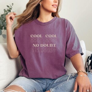 May include: A purple t-shirt with the text "Cool Cool Cool No Doubt No Doubt No Doubt" printed on the front.
