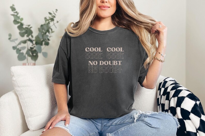 May include: A black cropped t-shirt with the text "COOL COOL COOL COOL NO DOUBT NO DOUBT" printed in a light pink color.