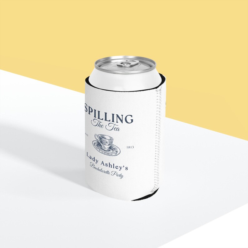 May include: White can cooler with a black zipper. The cooler has a design that says "Spilling the Tea" with a teacup and saucer illustration. The text "Lady Ashley's Bachelorette Party" is also on the cooler.