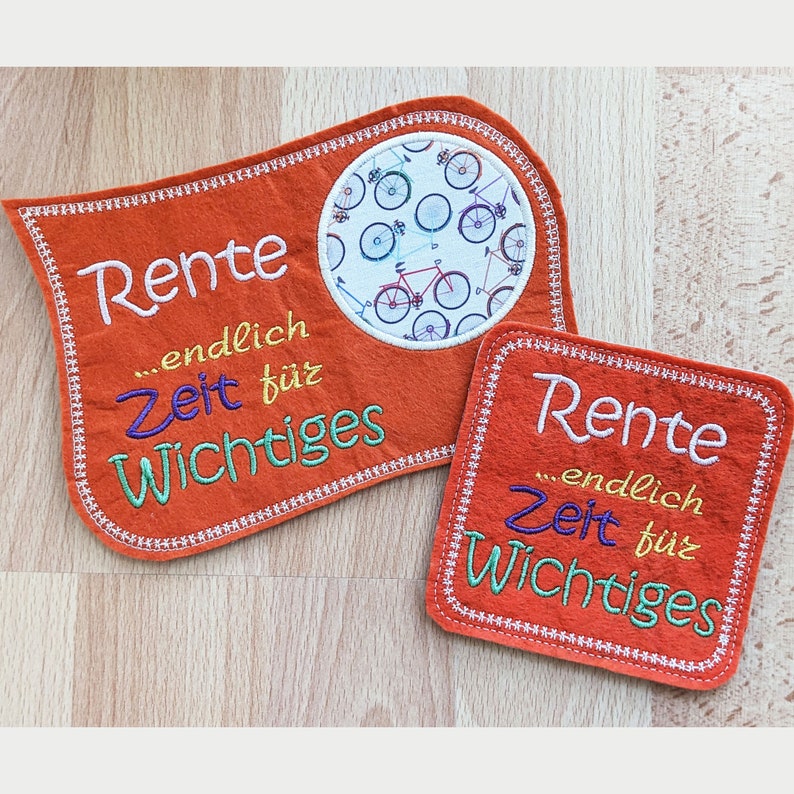 Puede incluir: Dos parches de fieltro naranja con texto bordado que dice "Rente...endlich Zeit f&uuml;r Wichtiges". Un parche tiene un c&iacute;rculo con fondo blanco y un patr&oacute;n de bicicletas de colores.