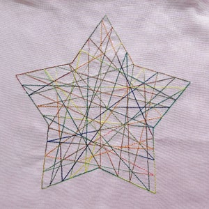 May include: A colorful star-shaped design embroidered on a light pink fabric. The star is filled with a network of intersecting lines in various colors, including red, blue, green, yellow, and orange.