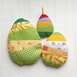 Peut inclure: Trois œufs de Pâques en tissu patchwork de couleur verte, jaune et rouge avec différents motifs. Les œufs sont faits de différents tissus cousus ensemble dans un style patchwork.