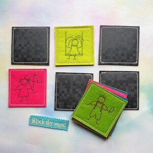 May include: A collection of colorful felt squares with embroidered designs. The squares feature a variety of images, including a girl with an umbrella, a girl on a swing, and a stick figure. The text "Stick dir was!" is also present.